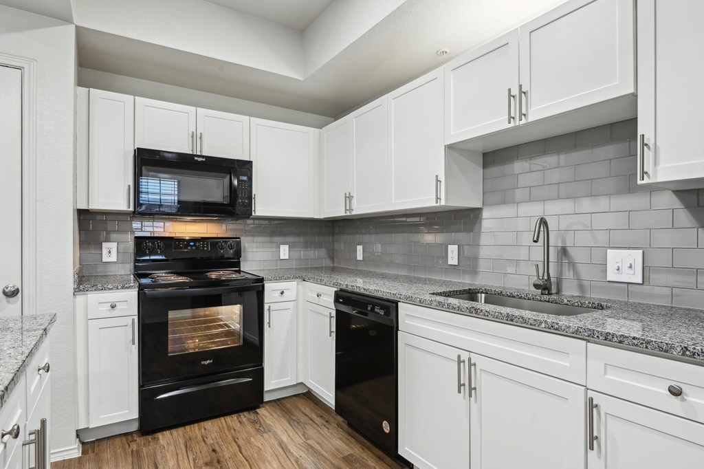 A kitchen with black appliances and white cabinets.