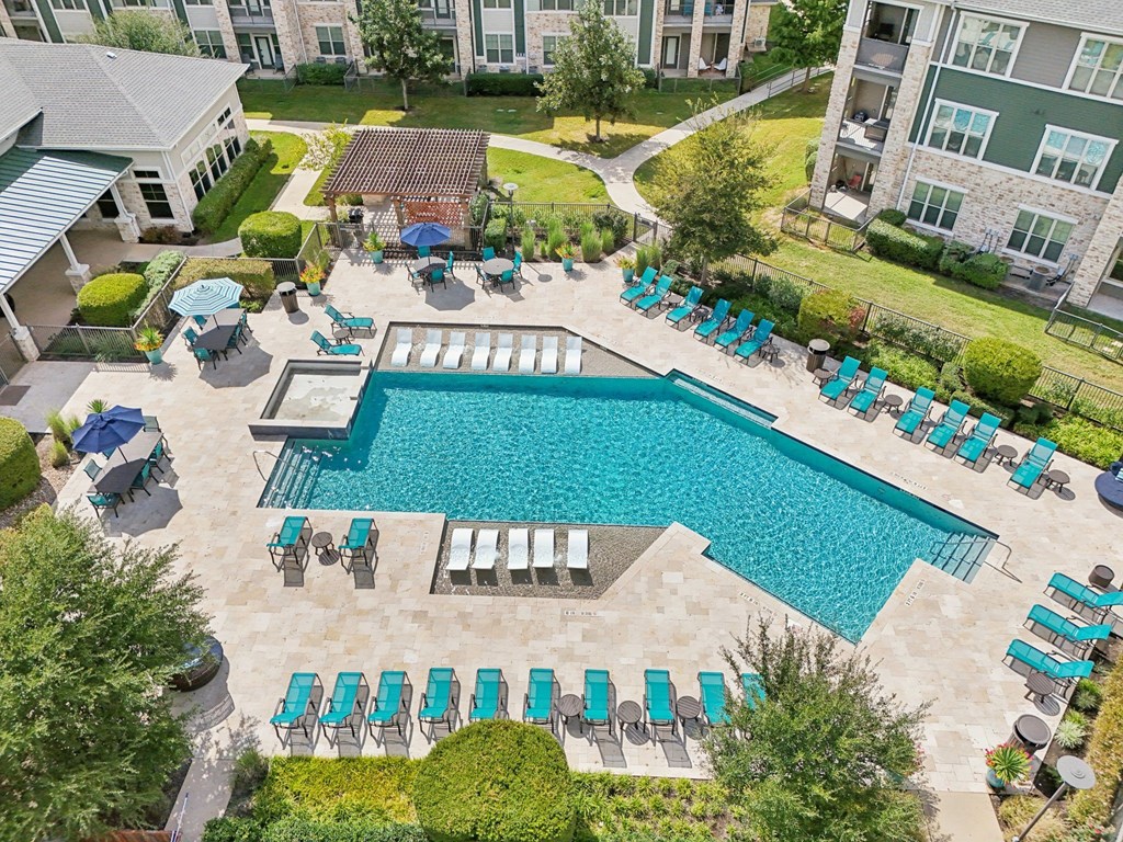 A large swimming pool surrounded by lounge chairs and umbrellas.