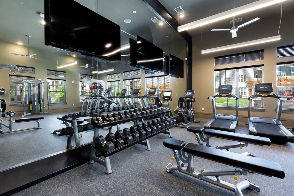 a gym with a row of weights and a large mirror at North Creek, Hutto, TX