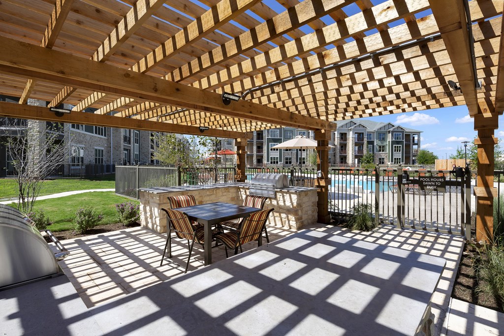 a patio with a table and chairs under a wooden pergola at North Creek, Hutto, TX