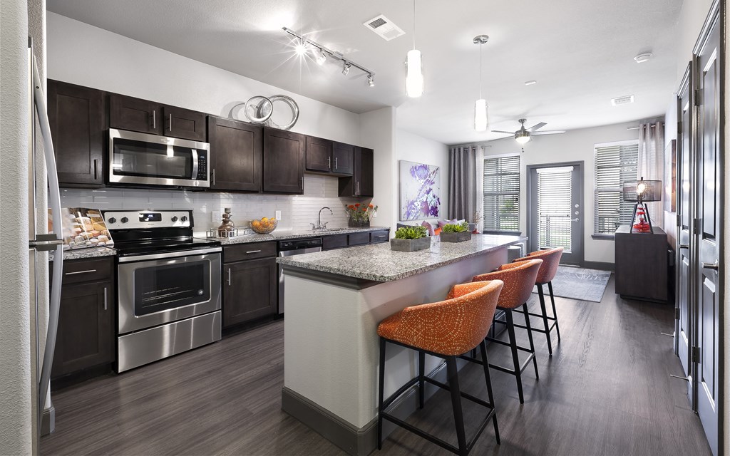 a kitchen with stainless steel appliances and a large island with chairs at North Creek, Texas, 78634