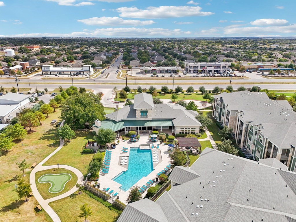 A large building with a pool in the foreground and a golf course behind it.