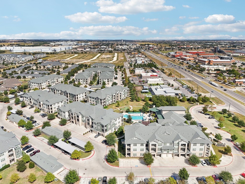 A bird's eye view of a residential area with multiple houses and a swimming pool.