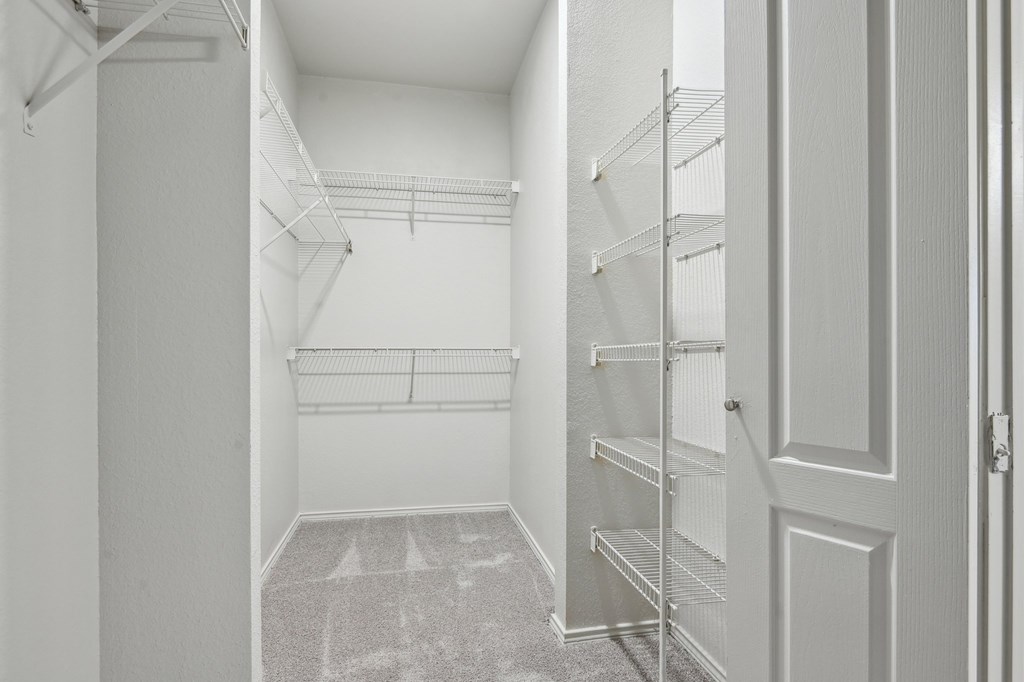 A white hallway with a carpeted floor and a door on the right.