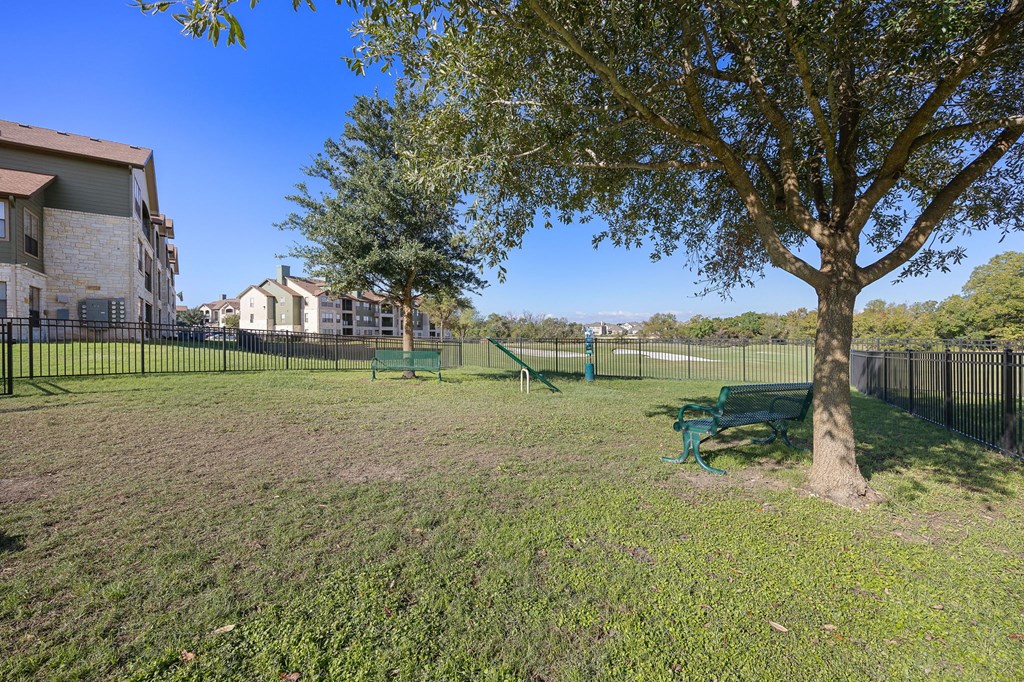 a park with a tree and a tennis court in front of a building at The Fairways at Star Ranch, Hutto, Texas
