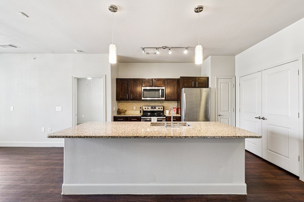 A kitchen with a granite countertop and stainless steel appliances.