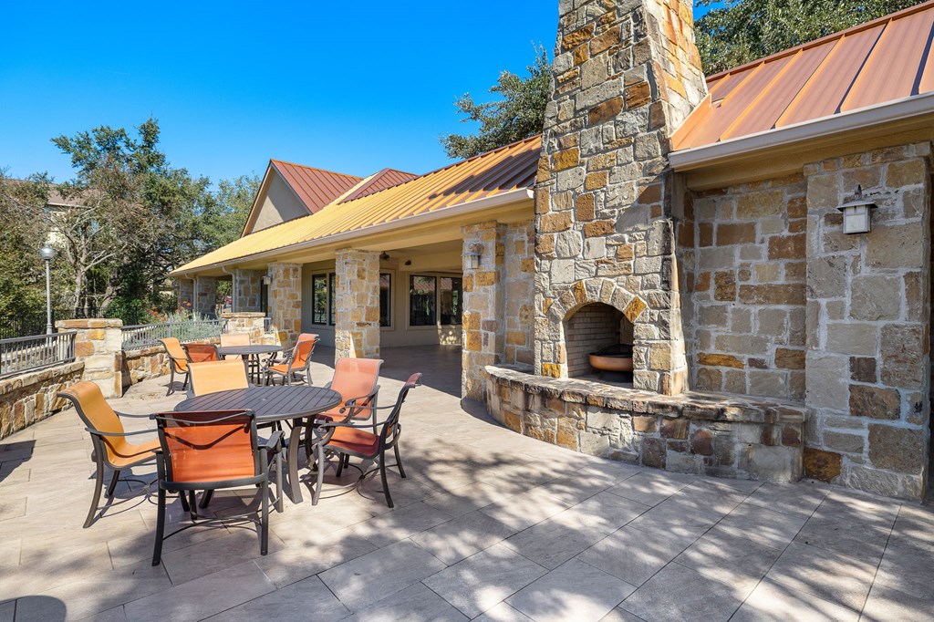 a backyard patio with a table and chairs and a stone fireplace at The Verandah, Texas, 78726