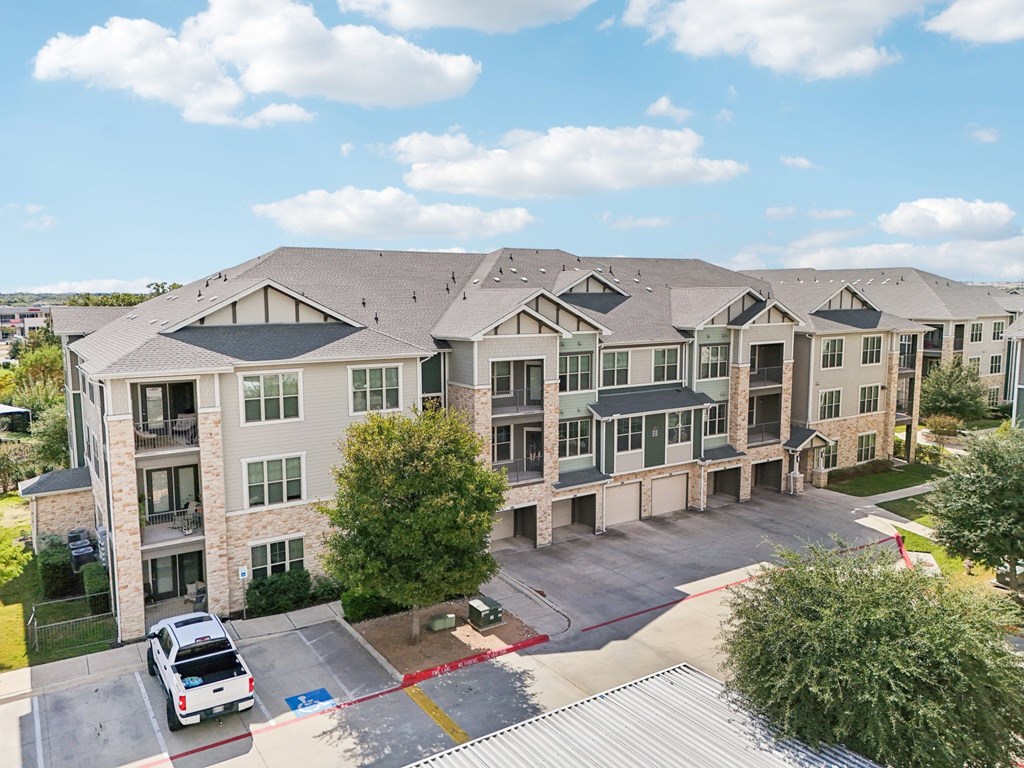 A large apartment complex with a parking lot in front.