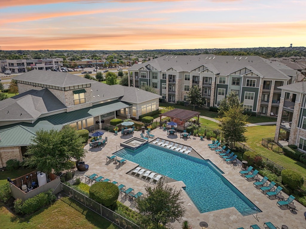 A large outdoor swimming pool surrounded by lounge chairs and umbrellas.