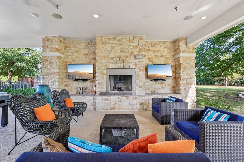 A patio with a stone fireplace and a TV mounted above it.