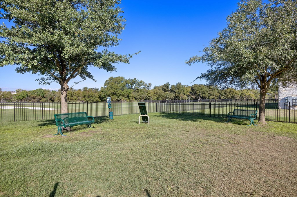 a park with benches and trees in front of a fence at The Fairways at Star Ranch, Hutto, Texas