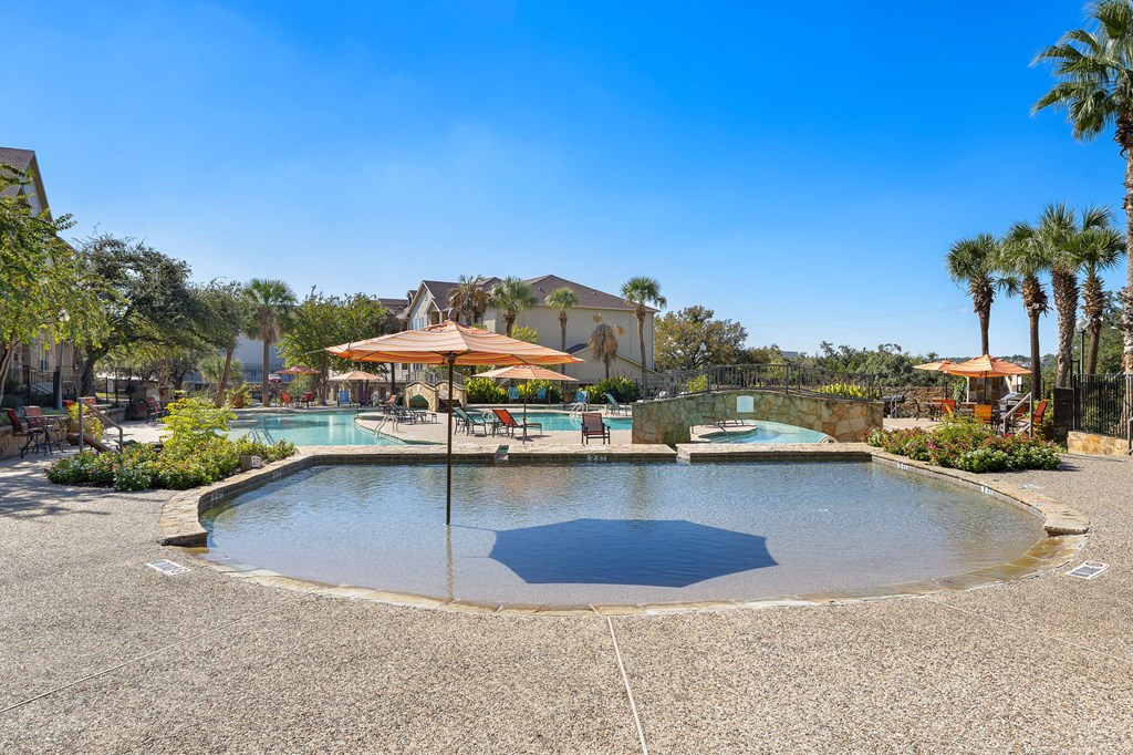 a swimming pool with umbrellas in front of a resort style pool at The Verandah, Austin, 78726