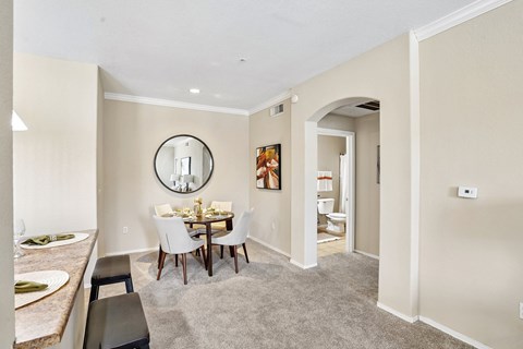 Dining area with round table and circular mirror at Adiamo Palm Valley Apartments, Arizona