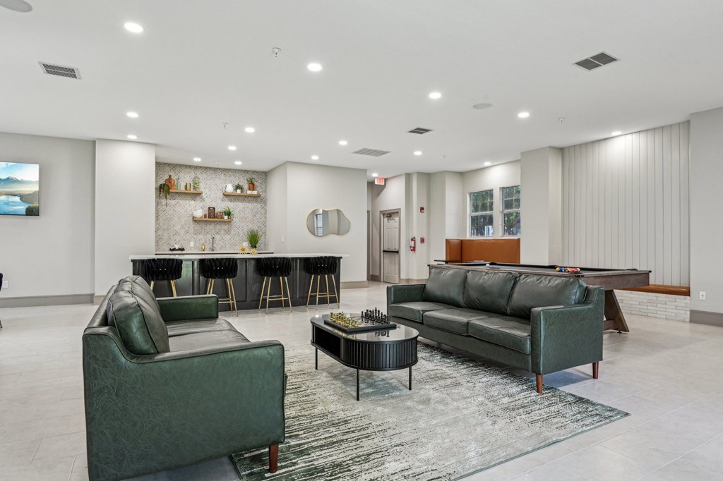 A living room with a green couch, a black coffee table, and a television.