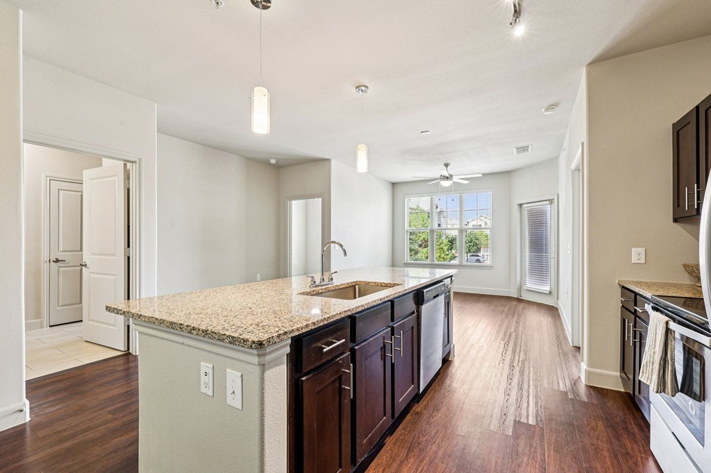 A kitchen with a granite countertop and dark wood cabinets.