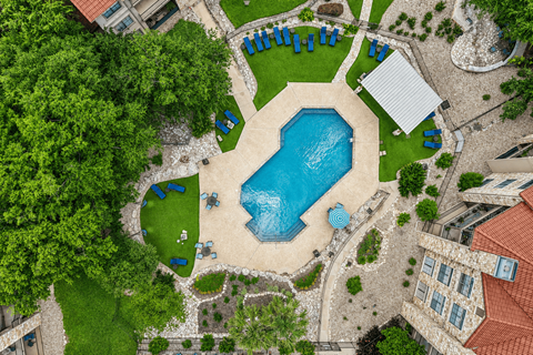 Aerial view of resort style pool with lounge chairs at Waters Edge Homes Apartments, Texas