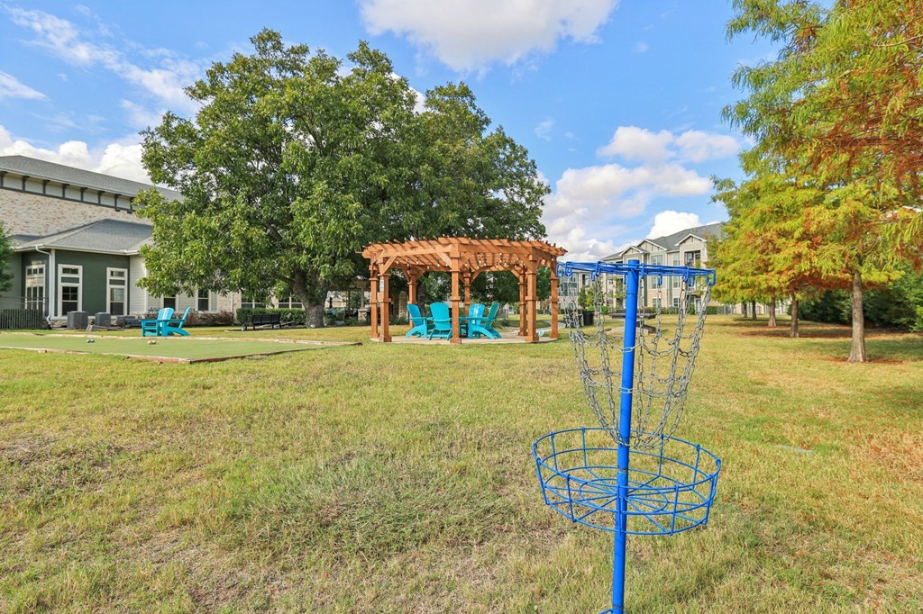 A blue disc golf basket sits in a grassy field.