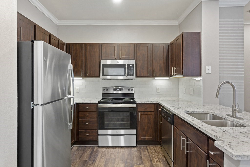 a kitchen with dark wood cabinets and stainless steel appliances at The Verandah, Austin, Texas