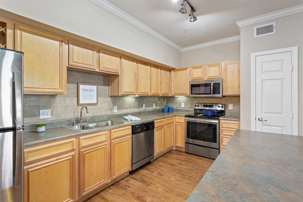 a kitchen with wooden cabinets and stainless steel appliances at The Verandah, Austin, TX