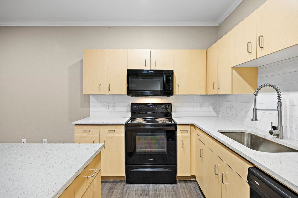 a kitchen with white quartz countertops and a black stove top oven at Artisan Apartments & Shops, Texas, 78729
