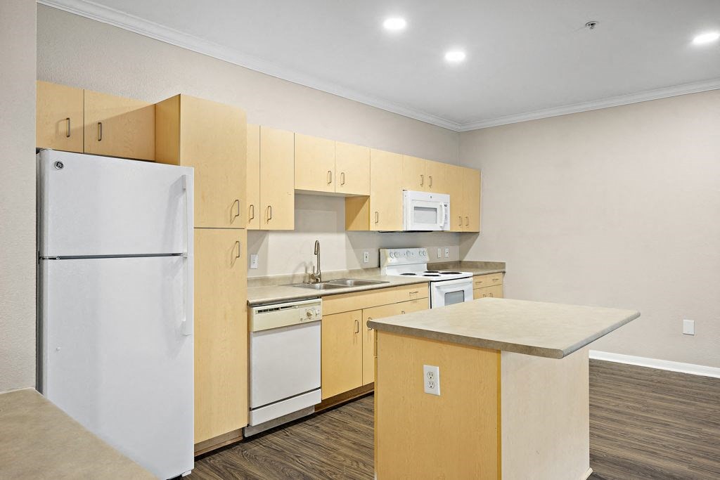 a kitchen with white appliances and wooden cabinets at Artisan Apartments & Shops, Austin, Texas