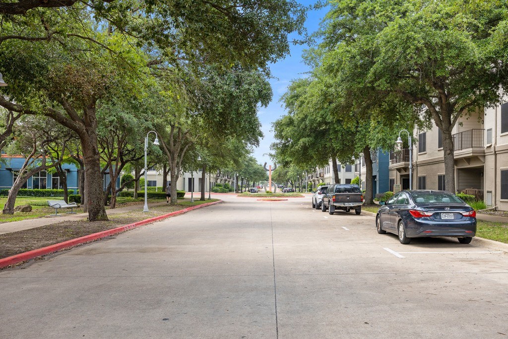 a tree lined street with cars parked on the side of the road at Artisan Apartments & Shops, Austin