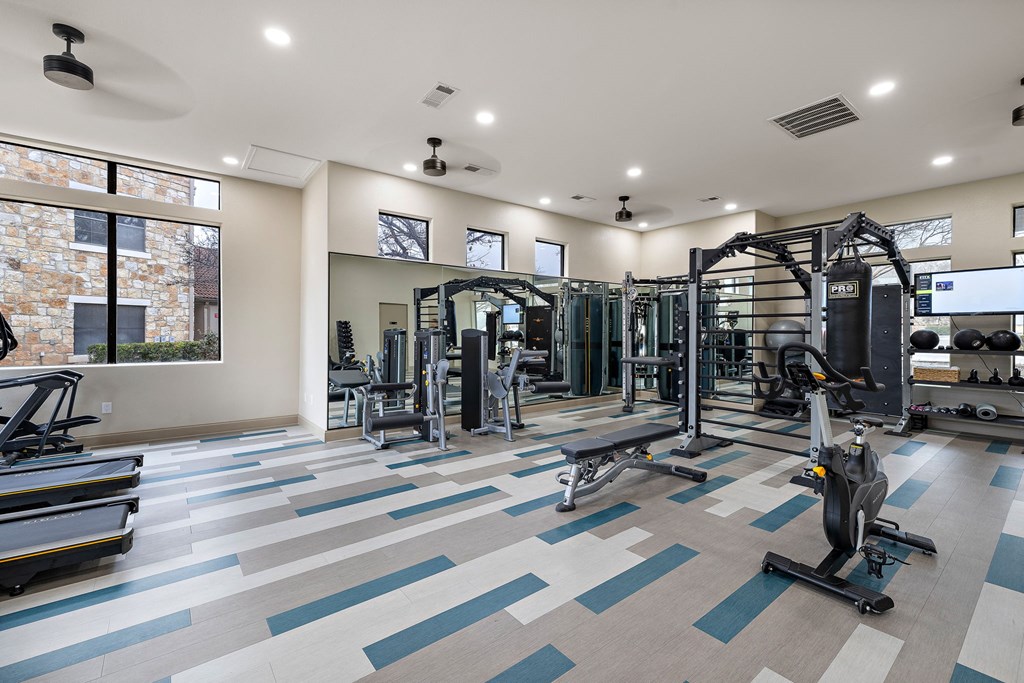 a gym with weights and cardio equipment and a large window at Waters Edge Apartment Homes, Georgetown, TX, 78626