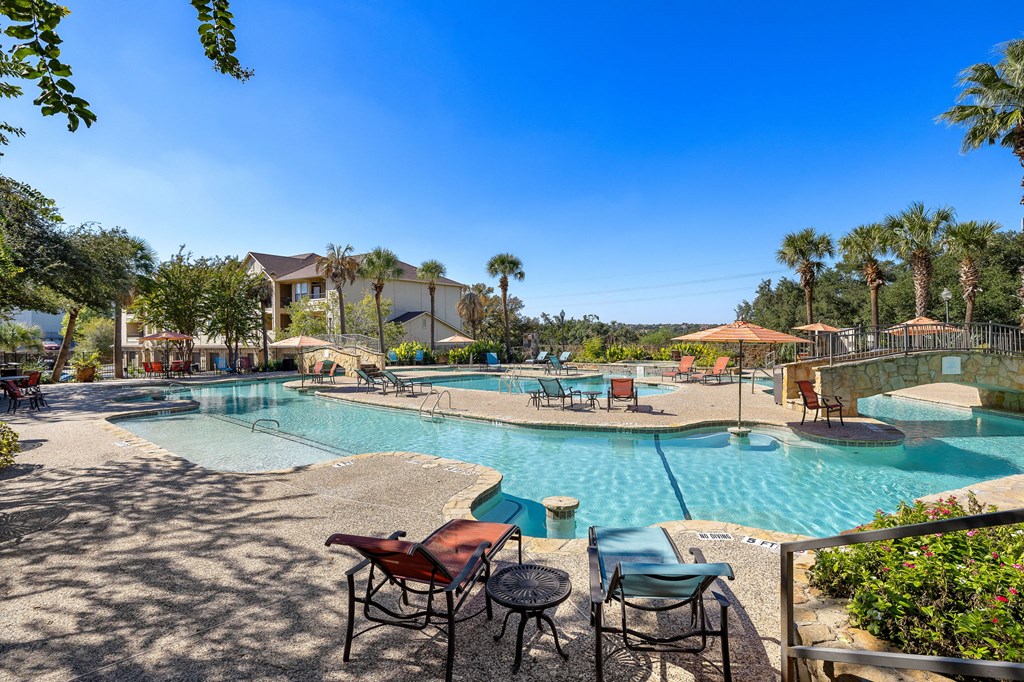 a resort style swimming pool with tables and chairs around it at The Verandah, Austin, TX, 78726