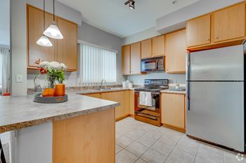 A kitchen with wooden cabinets and a granite countertop. at Adiamo Palm Valley, Goodyear, AZ