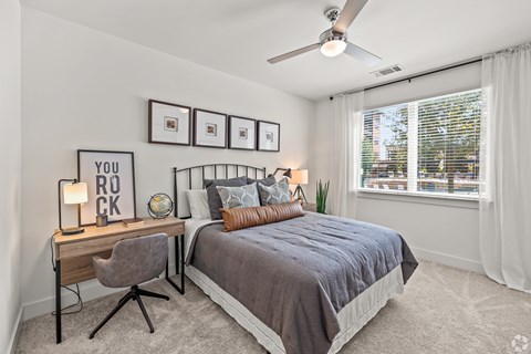 A bedroom with a bed, desk, chair, and pictures on the wall.