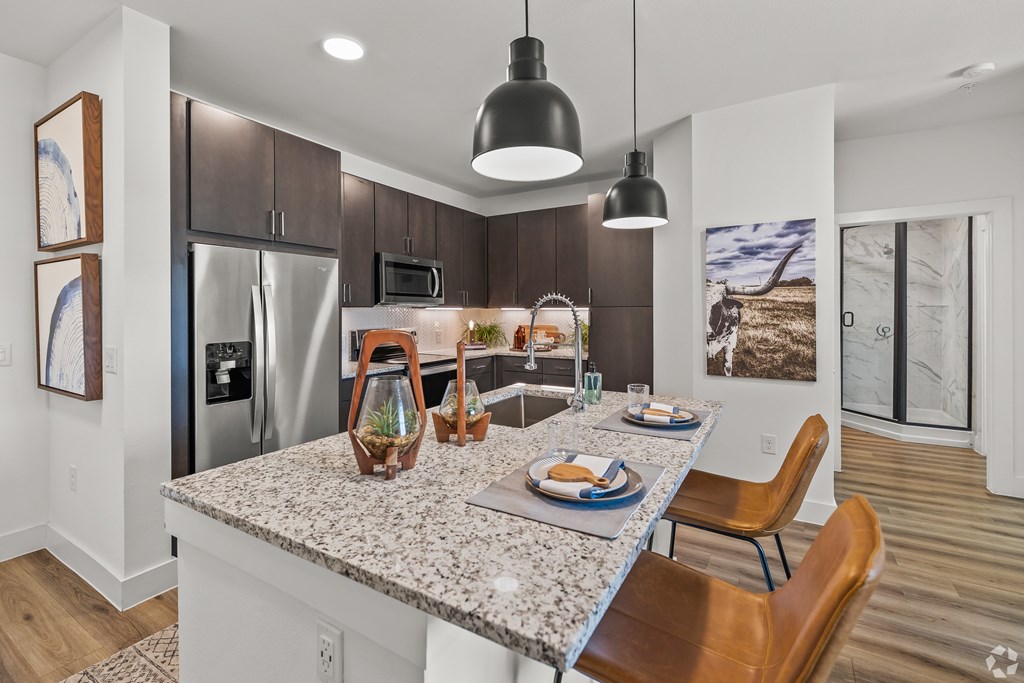 A modern kitchen with a granite countertop and stainless steel appliances.