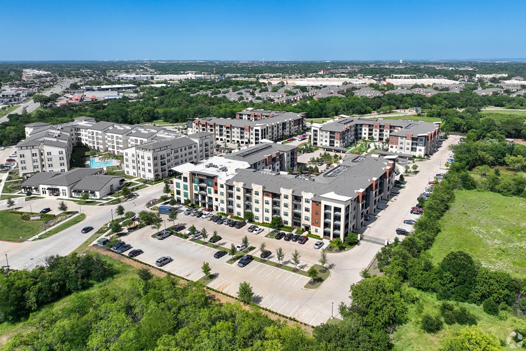A bird's eye view of a large apartment complex surrounded by greenery and roads. at Aurora Watson Branch, Texas