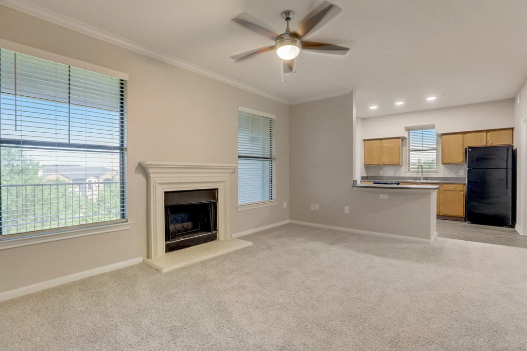 an empty living room with a fireplace and a kitchen
