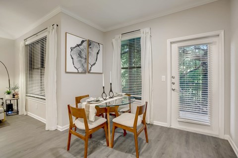 A dining room with a table set for two and a plant on the side table.