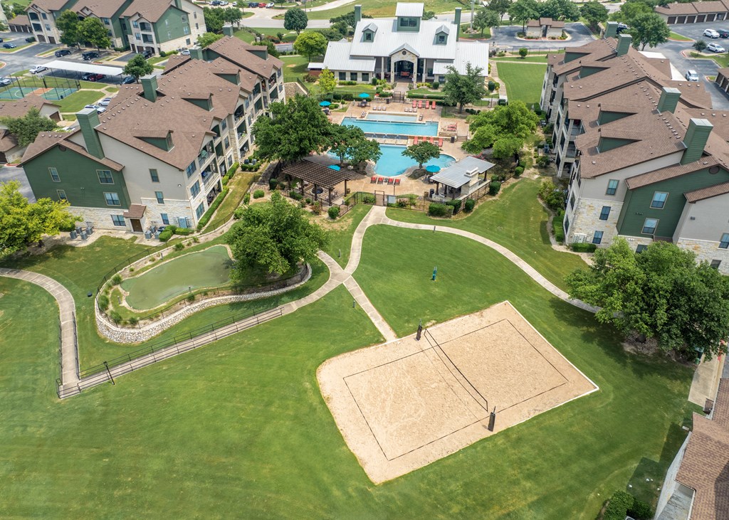 an aerial view of an apartment complex with a swimming pool and lawn