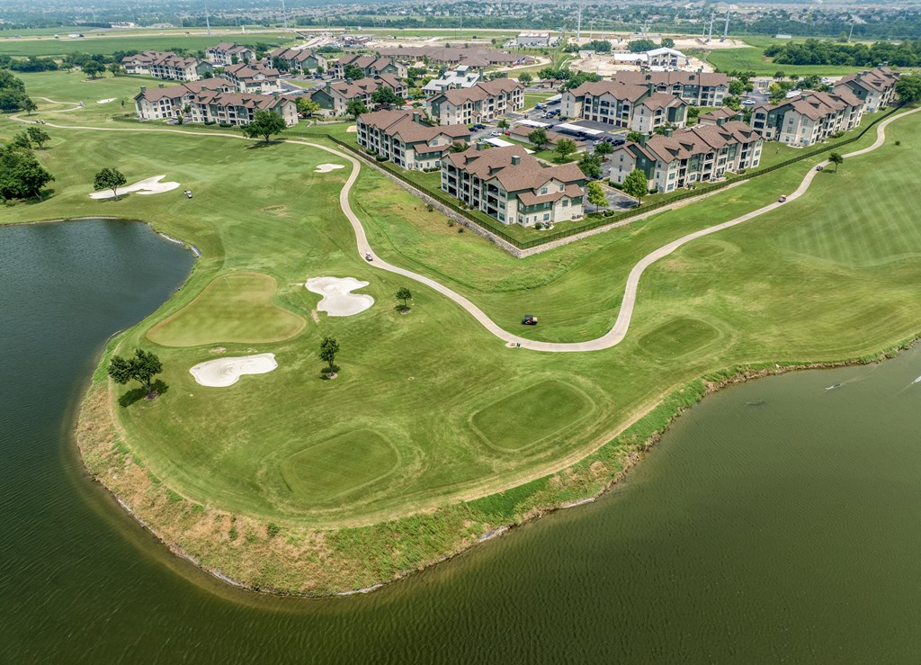 an aerial view of a golf course next to a body of water and a city
