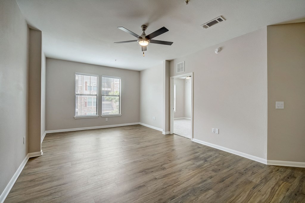 an empty living room with hard wood floors and a ceiling fan