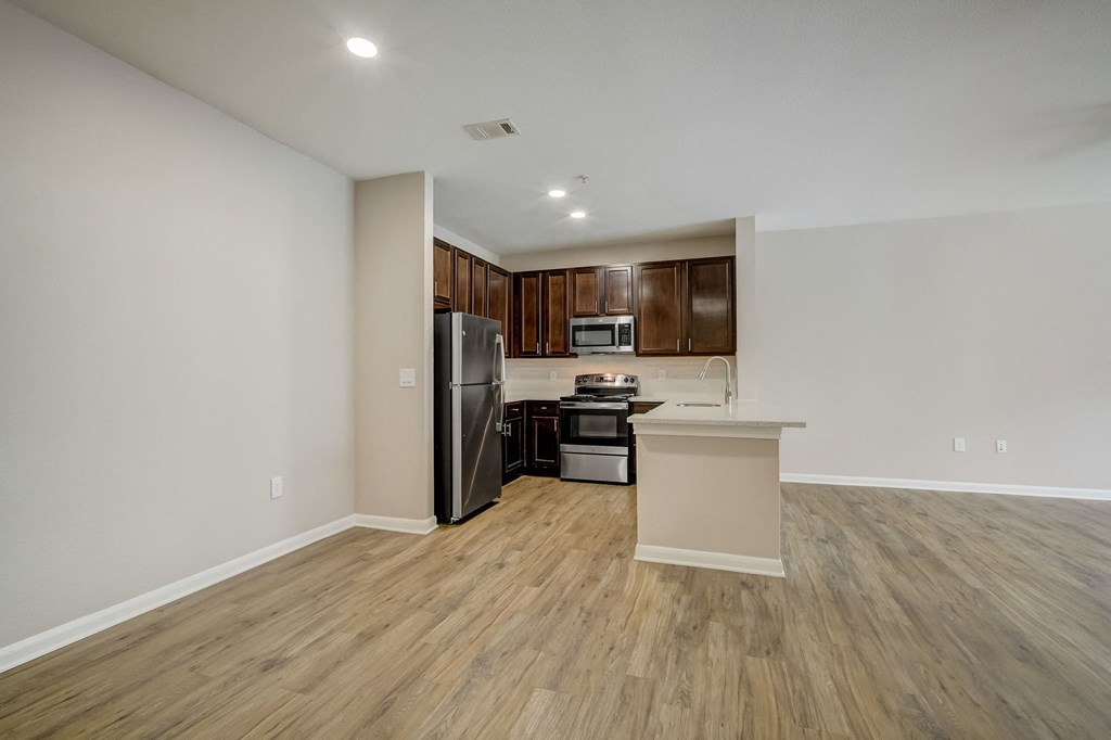 a kitchen with wood flooring and a stainless steel refrigerator