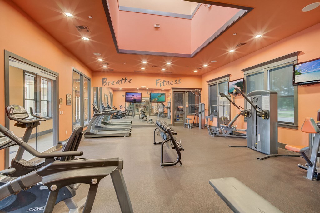 a gym with treadmills and other exercise equipment in a building with orange ceilings