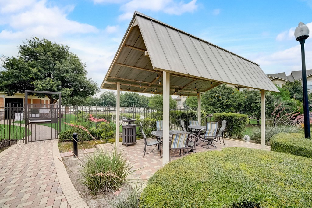 a pavilion with a table and chairs on a brick patio