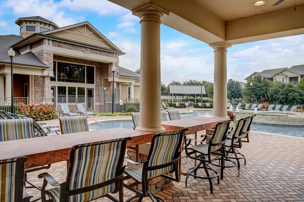 an outdoor bar with chairs and a pool in front of a house