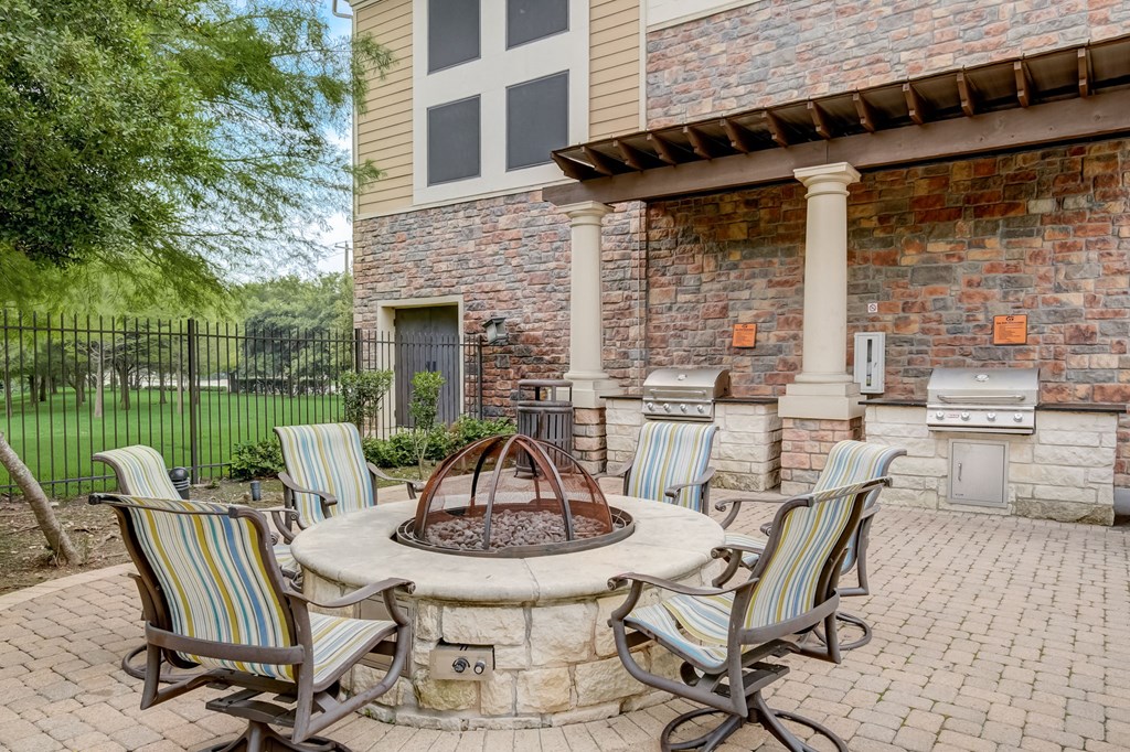 a patio with a fire pit and chairs around it