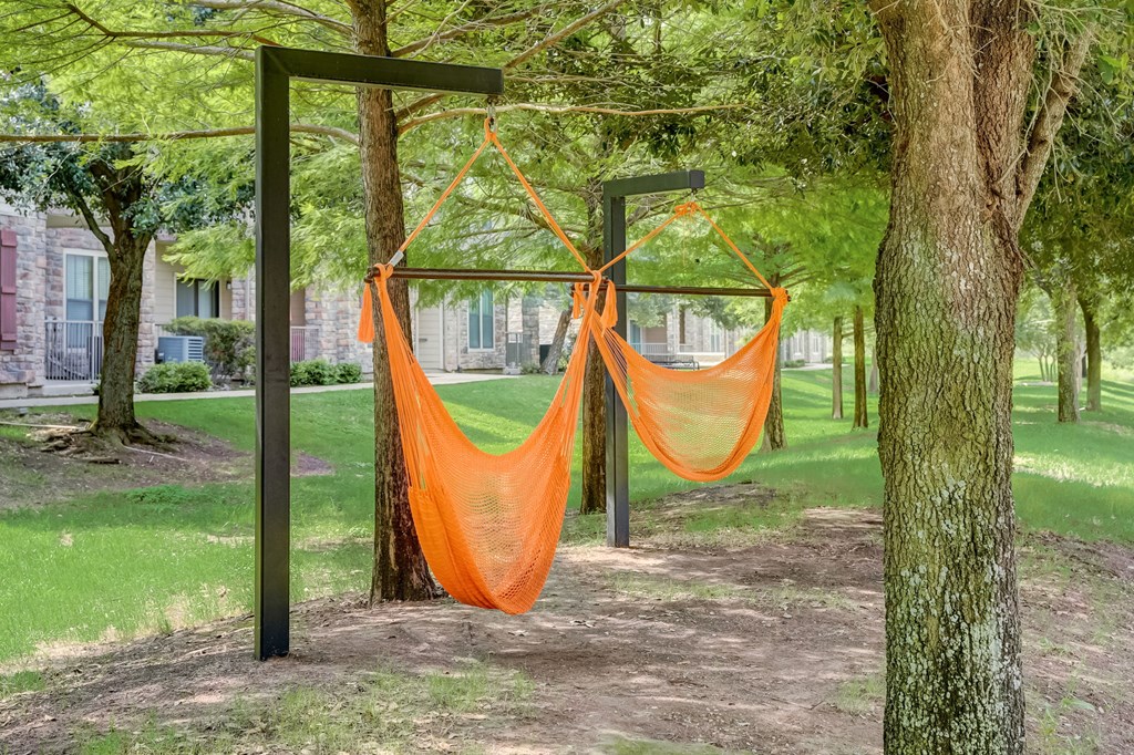 a hammock in the shade of trees in a park