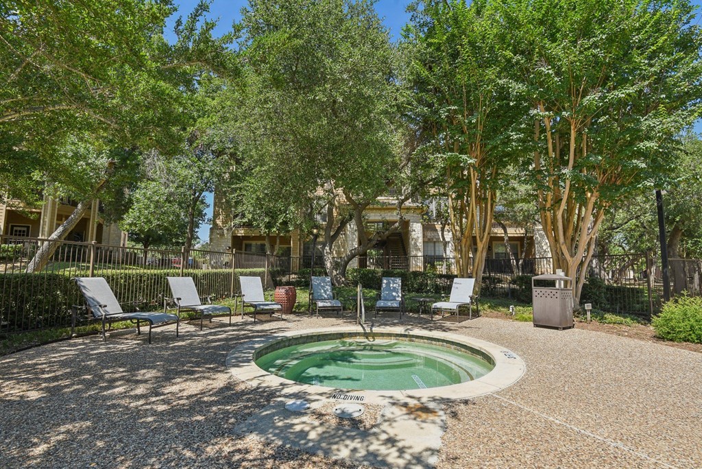 a small fountain with chairs around it in a courtyard with trees at Sonterra Apartment Homes, Austin, 78726