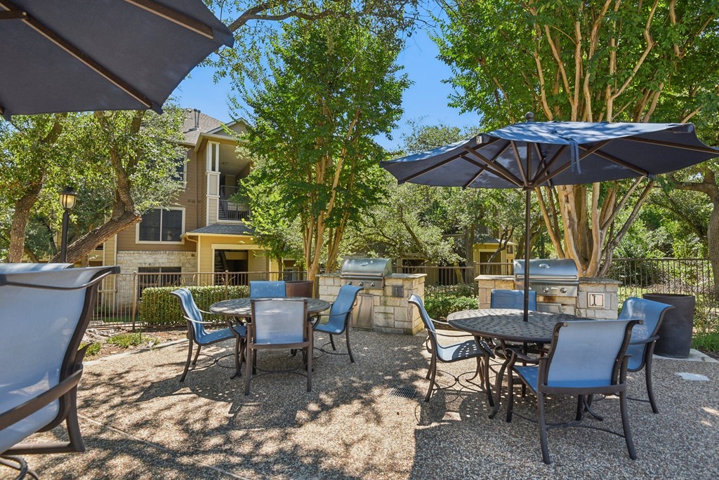 an outdoor patio with tables and chairs and umbrellas at Sonterra Apartment Homes, Austin, 78726