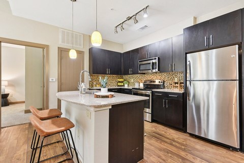 a kitchen with black cabinets and a stainless steel refrigerator