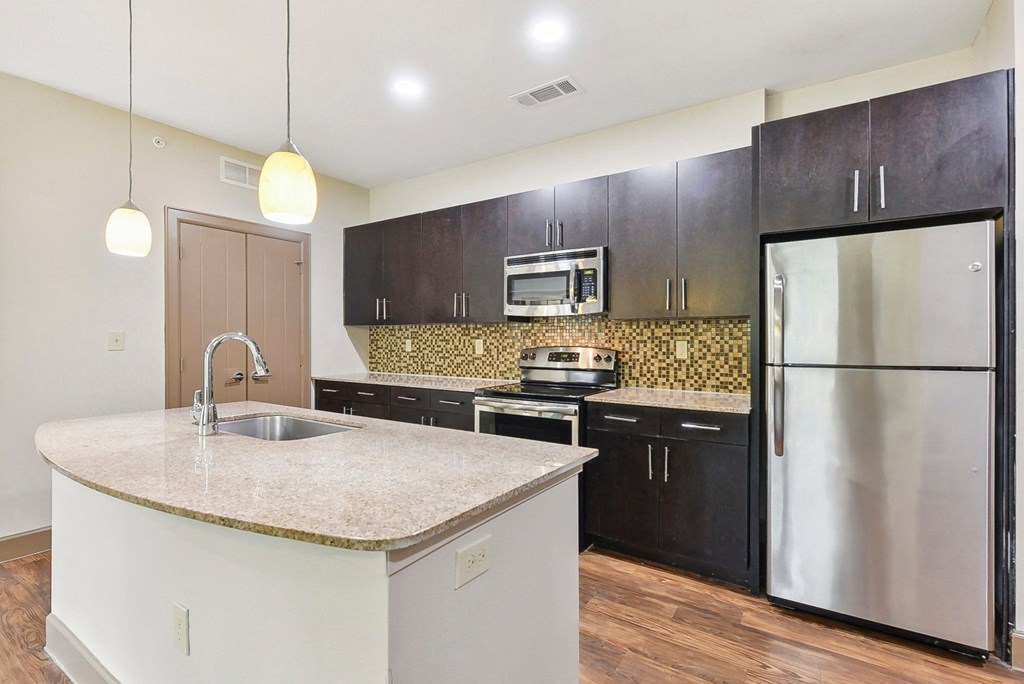 a kitchen with stainless steel appliances and a marble counter top at Lakeline East Apartments, Texas