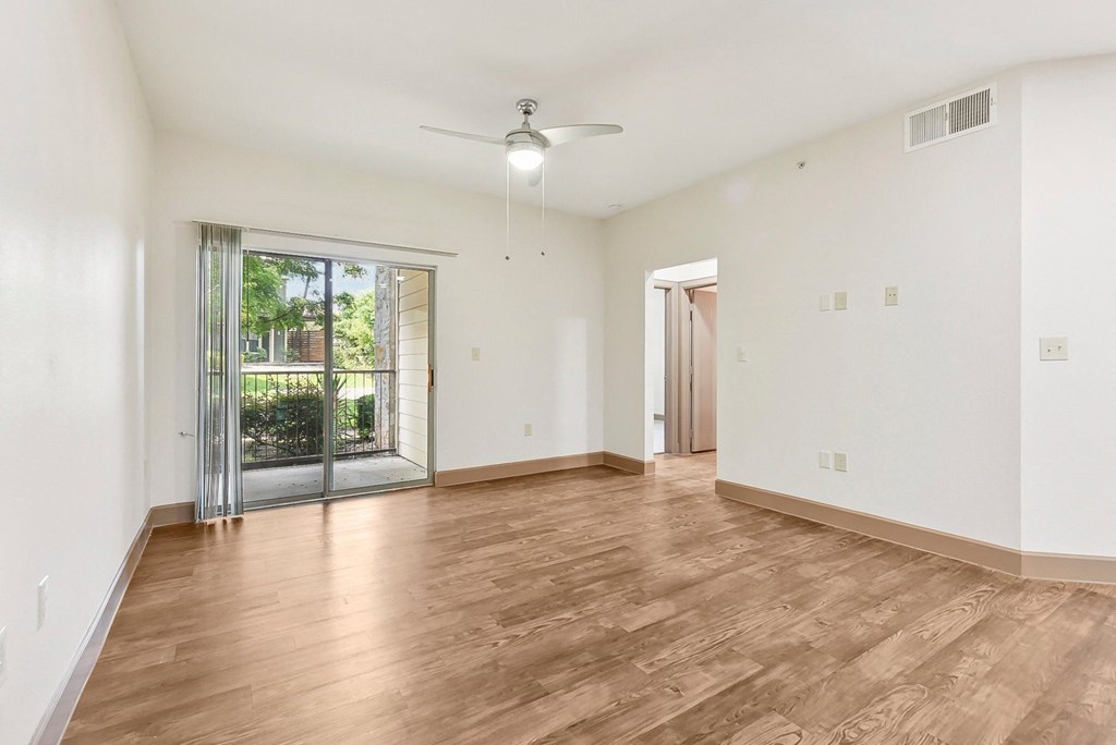 an empty living room with a sliding glass door to a patio at Lakeline East Apartments, Cedar Park