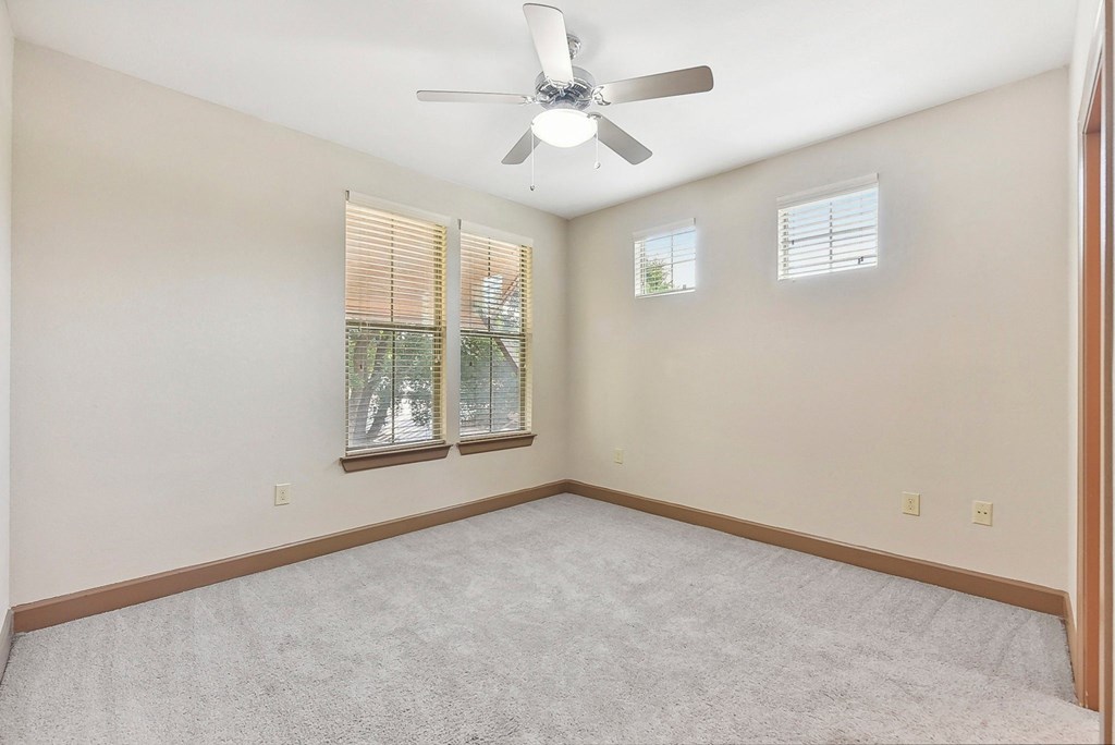 an empty room with a ceiling fan and two windows at Lakeline East Apartments, Texas, 78613