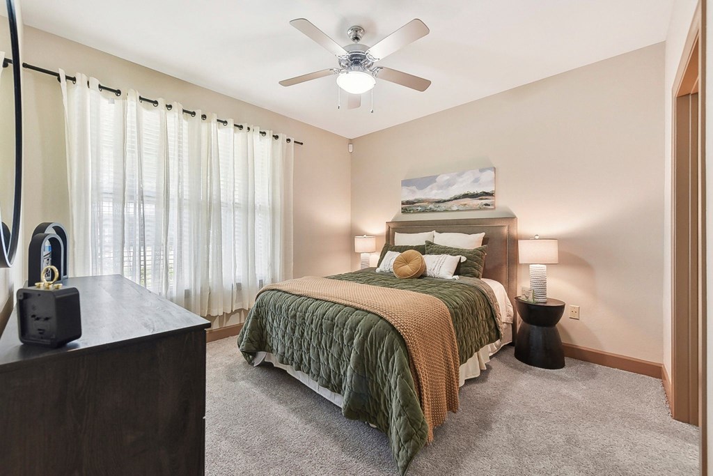 a bedroom with a large bed and a ceiling fan at Lakeline East Apartments, Cedar Park, TX
